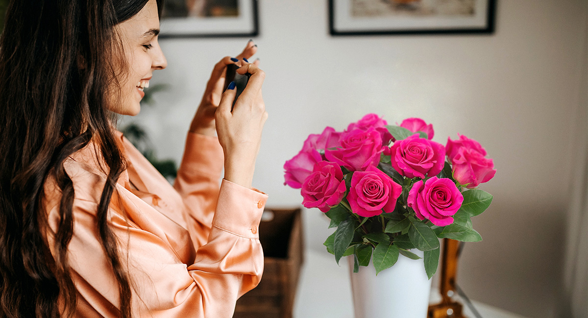 a woman taking a photo of gift bouquet of roses
